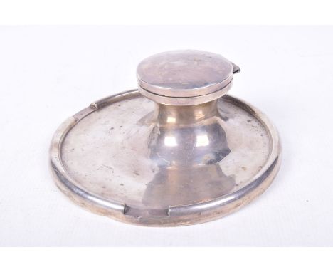 A large weighted silver ink wellThe circular hinged cover revealing a ceramic ink well mounted on a circular tray base, diame