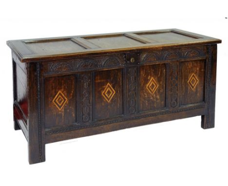 A CARVED AND INLAID OAK CHEST WITH THREE PANEL LID AND FRONT, THE INTERIOR WITH A LIDDED TILL