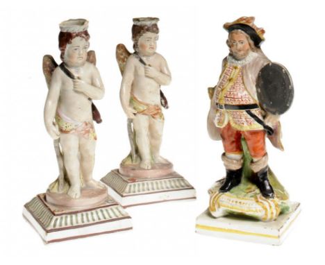 TWO PEARLWARE PUTTO FIGURAL CANDLESTICKS ON SQUARE BASE WITH OVERGLAZE ENAMEL DECORATION, CIRCA 1820 AND A CONTEMPORARY STAFF