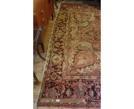 A Persian Heriz-style carpet, with faded red ground and central motive.