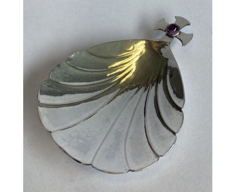 A E JONES: A large fluted silver caddy spoon mounted with amethyst terminal. Birmingham 1904. Approx. 29 grams.
