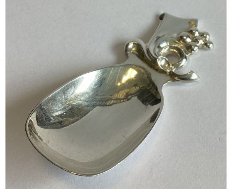 R E STONE: A heavy cast silver caddy spoon with scroll decoration. London 1946. Approx. 30 grams.