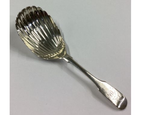 DUBLIN: A large Irish silver fiddle pattern caddy spoon of fluted form. By NS. Approx. 17 grams.