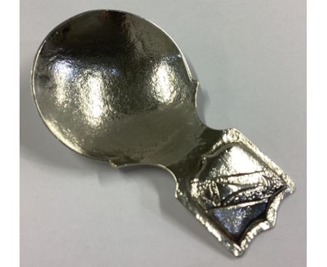 A silver shield-shaped caddy spoon with textured bowl. Birmingham 1958. By BI. Approx. 21 grams.