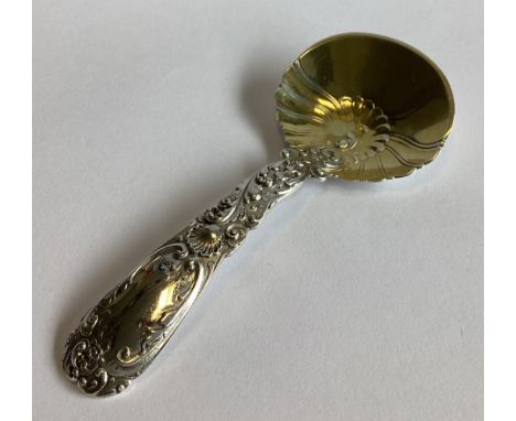 A heavy Sterling silver and silver gilt caddy spoon with chased decoration. Approx. 31 grams.