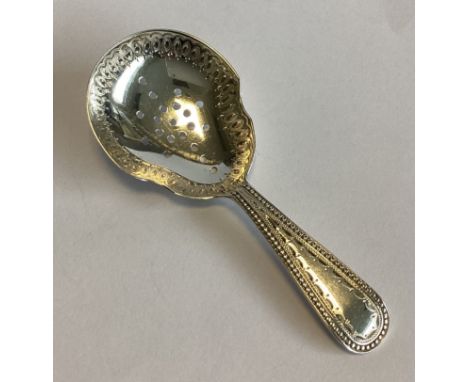 EXETER: A large silver bead edge caddy spoon with engraved and pierced bowl. By JW&Co. Approx. 15 grams.
