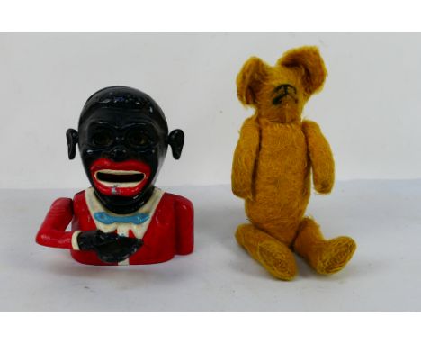 A vintage aluminium mechanical money bank and a small soft toy bear. [W]Note: Mechanical cast iron banks were first manufactu