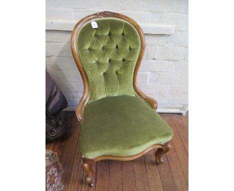 A carved beech nursing chair with castors and light green velvet upholstery 