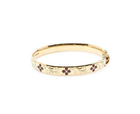 A diamond and ruby 9ct gold hinged bangle, comprising three floral details, each set with round cut ruby petals with diamond 