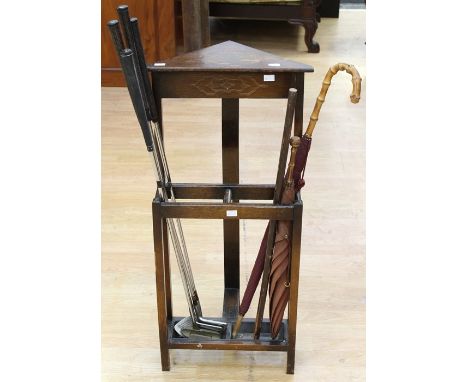 A 20th century umbrella/stick stand, containing two umbrellas, and four various golf clubs.