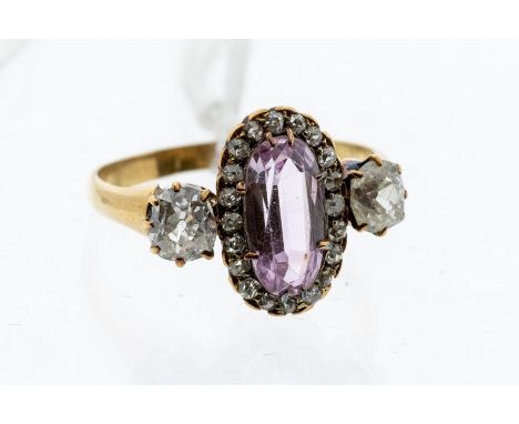 A late 19th Century diamond and pink topaz 18ct gold ring, comprising a central oval cut pink topaz approx 10 x 4mm, within a