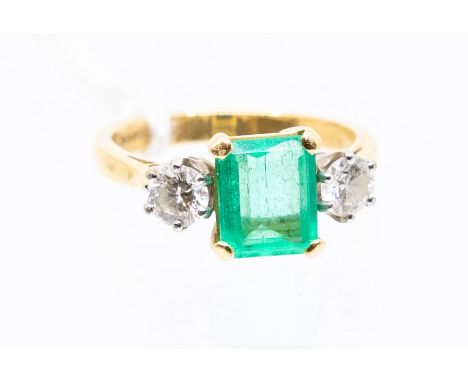 A emerald and diamond 18ct gold ring, comprising a central claw set emerald cut emerald approx 8 x 6mm, with brilliant cut di