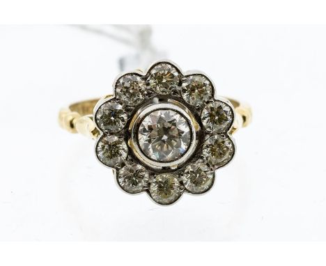 A diamond and 18ct yellow gold cluster ring, comprising a rub over set brilliant cut diamond set to the centre, within a a bo