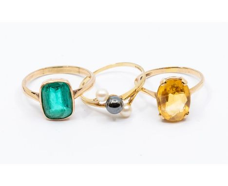 A collection of three 9ct gold dress rings to include a claw set oval citrine ring, size Q, a cushion shaped green paste ring