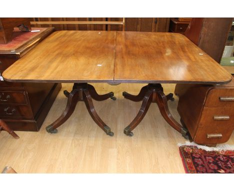 A Regency style mahogany twin pillar pedestal extending dining table, complete with an extra leaf, vase turned columns having