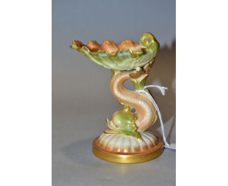 A ROYAL WORCESTER BLUSH IVORY SWEETMEAT DISH, shape no G49, modelled as a shell supported by a dolphin on a lobed circular ba