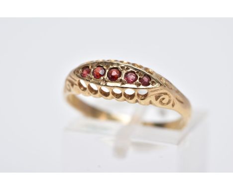 A 9CT GOLD FIVE STONE RING, designed with a row of five circular cut garnets, within an openwork gallery and scroll detailed 