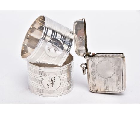 TWO SILVER NAPKIN RINGS AND A SILVER VESTA, each napkin ring of a circular form, engine turn design with engraved 'S' and 'R'