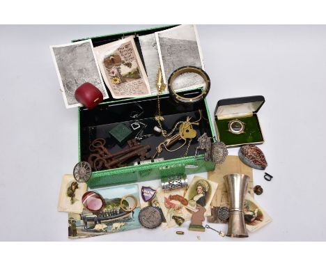 A GREEN TIN WITH CONTENT, to include a white metal double sided liquour measuring cup, a brass inlaid carved horn bangle, a y