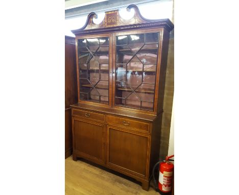 A GEORGIAN/EDWARDIAN MAHOGANY CABINET BOOKCASE, the inlaid swan-neck pediment above twin thirteen pane astragal doors, the la