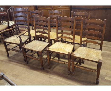A SET OF SEVEN 20TH CENTURY OAK AND ASH LADDER BACK DINING CHAIRS with rush seats, raised on turned legs with pad toes united