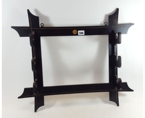 A LATE 19TH CENTURY EBONISED AND GILDED THREE BRACKET WALL HANGING SWORD RACK, 23 1/2 ins wide x 20 ins high.   