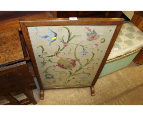 An oak framed and embroidered firescreen
