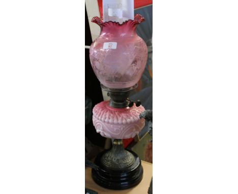 Victorian cranberry coloured oil lamp with shaped font and etched cranberry shade, the shade with butterfly detail, raised on