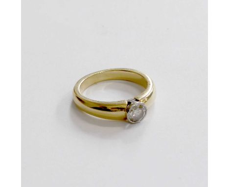 An 18 Carat Gold Diamond Solitaire Ring, the round brilliant cut diamond in a white rubbed over setting, to a yellow plain po