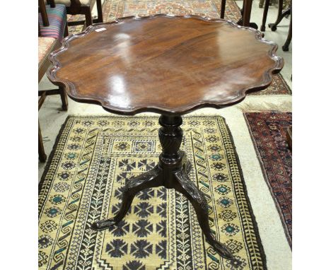 A George III mahogany tea table, the circular top with pie-crust rim, raised on a turned and wrythen carved pedestal to carve