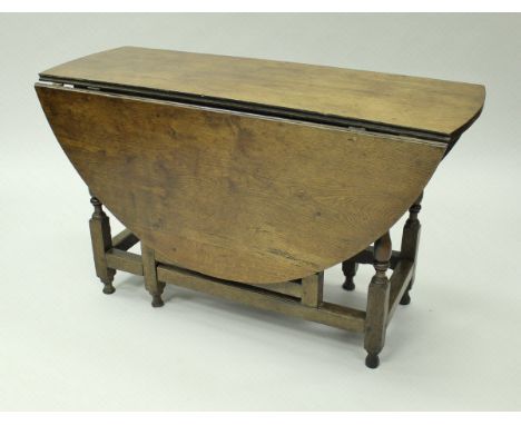 An 18th Century oak oval gate-leg drop-leaf dining table with single end drawer on baluster turned and ringed supports to blo