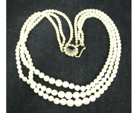 A graduated pearl three strand necklace with nine carat gold mounted seed pearl and garnet clasp and a 9 carat gold cased Rot