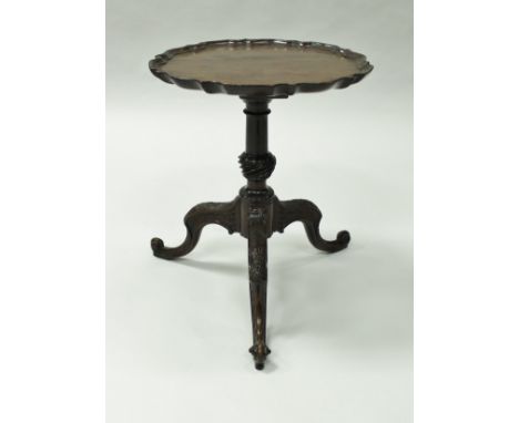 A mahogany wine table in the George III taste, the circular top with pie-crust rim, raised on a turned and wrythen carved ped