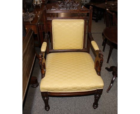 An Edwardian carved mahogany armchair, with primrose brocade upholstered back panel, arm rests and seat, raised on turned flu