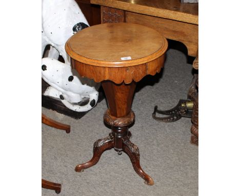 A Victorian walnut trumpet shaped sewing table, the hinged top lifting to reveal a partitioned interior, raised on foliate ca