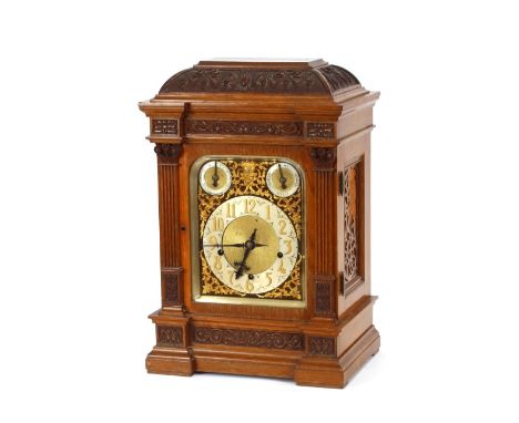 A large Edwardian carved oak chiming mantel clock, with brass spandrelled and steel dial, 56cm high x 36cm wide