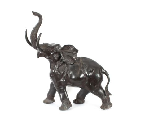 A bronze model of an elephant, with it's trunk raised aloft, 73cm long x 79cm high