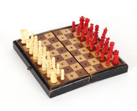 A red stained and natural ivory travelling chess set, contained in a folding wooden box