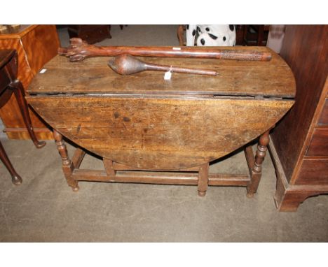An Antique oak gate leg dining table, the rounded drop leaves raised on turned baluster supports united by stretchers, fitted