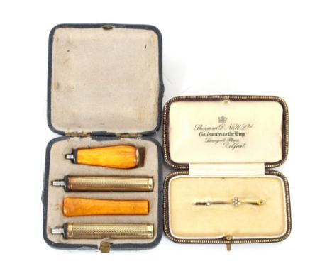 A yellow metal and engine turned decorated sectional cigarette holder, with amber mouth piece and end section, cased; and a V