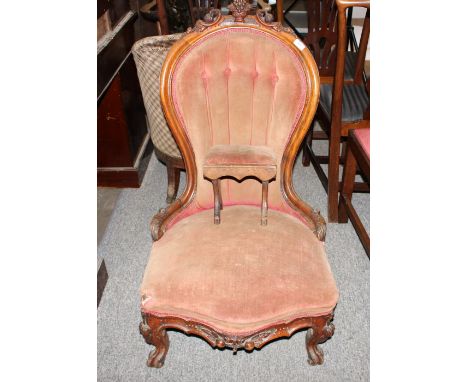 A Victorian walnut framed spoon back nursing chair, having foliate and fruit carved cresting, raised on cabriole front suppor