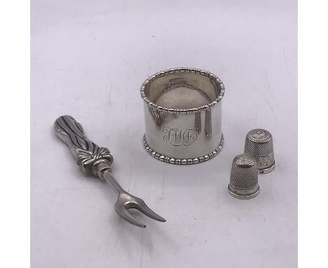 A small selection of silver items to include two thimbles, a napkin ring and fork