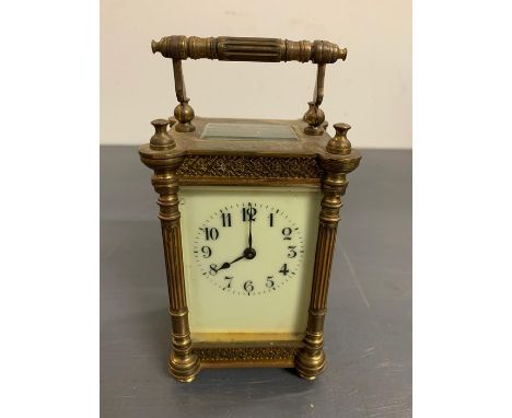 A brass carriage clock with enamel face and column sides