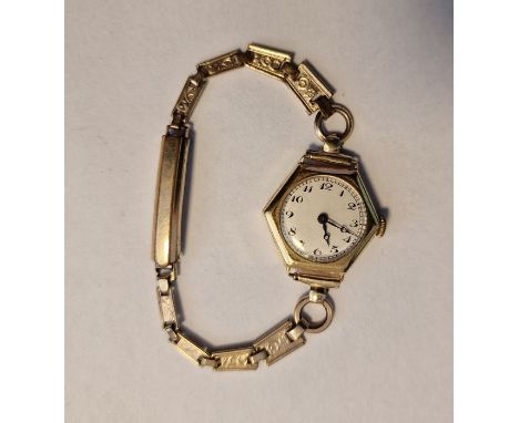 Lady’s gold wristwatch with white enamel circular dial, Arabic numerals, within hexagonal case and the gold-coloured engraved