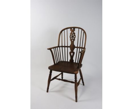 An elm and ash Windsor chair, late 19th century, with wheel and stick back above a saddle seat and raised on pilaster legs jo