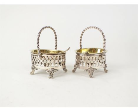 A pair of white metal oval salts, each with pierced decoration, rope twist basket handle, removable liner and raised on four 