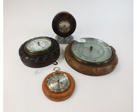 Three aneroid barometers and a desk clock The barometers of circular wood-mounted type, largest 27cm dia., the desk clock wit