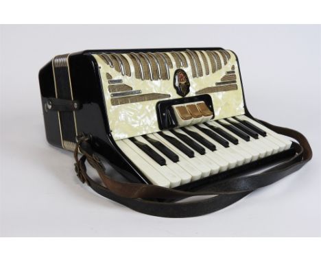A German cased piano accordion with 26 note keyboard and various song sheets.