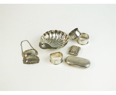A silver butter dish in the form of a shell with butter knife, Atkin Brothers, Sheffield, together with three silver napkin r