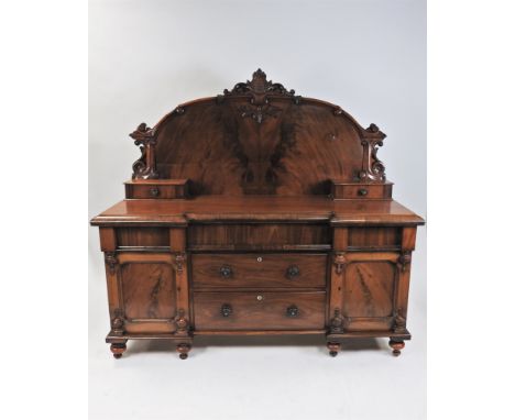 A Victorian figured mahogany sideboard, the panel back surmounted by a scallop shell bracket moulding and with two gallery dr